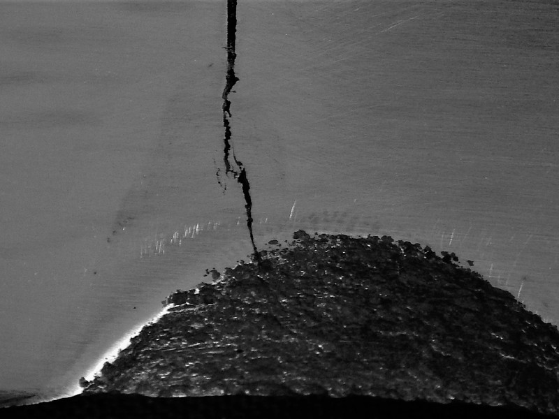 Macrographic detail of the cracked position close to the actuator hole.  The through wall crack presented a branch aspect in the weld metal, that is the original defect created during welding, and a straight aspect when propagating from the repair.