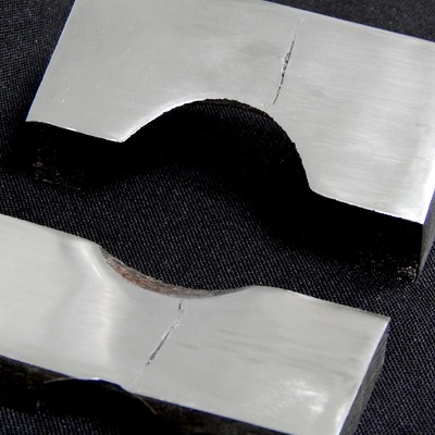 Longitudinal section of the cylindrical body showing two pieces with the cracks, close to the position of the actuator hole.  The valve body thickness is 40 mm at the location where the cracks appeared.