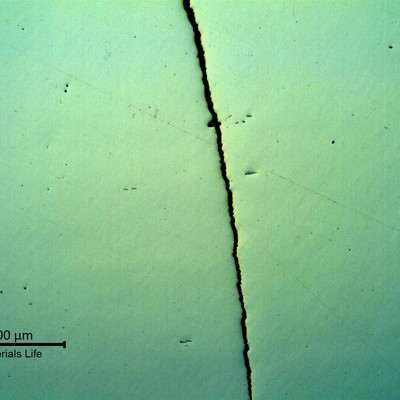 Micrography in low magnification, as polished, of the crack in the valve thickness,  showing the straight aspect of the fatigue propagation.