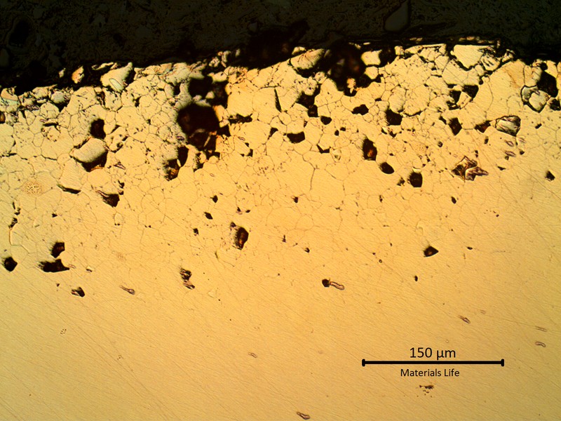 Micrographic detail of the external side of the bent tube, as polished, showing detachement of several grains due to the intergranular corrosion layer. The corroded layer is about 200 microns thick at this position.