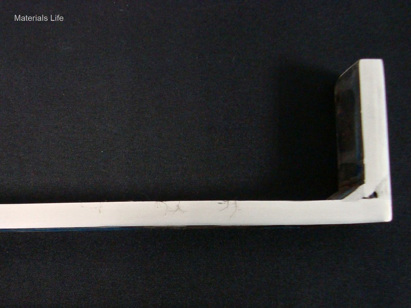 Macrography of the longitudinal section of the stub end, showing the external side to the top and the internal side to the bottom. The stub end was manufactured by welding, longitudinal seam (not evidenced in this image) and circunferential weld of tube to disc (partial penetration). The cracks starts from the external side of the stub end.