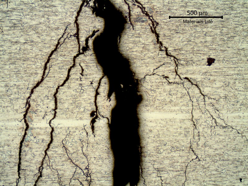 Micrography of the stub end in the middle of the thickness, outer diameter to the top of the image, presenting multiple branched cracks.