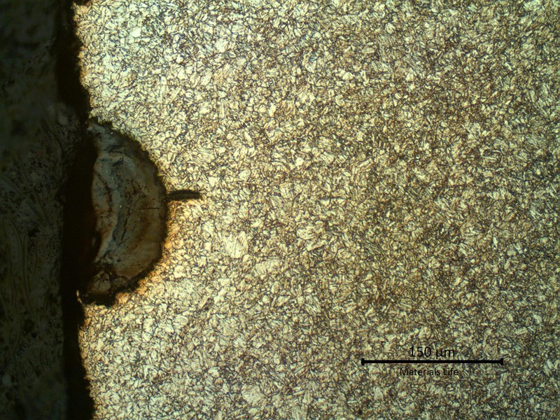 Micrography of a longitudinal section of the pipe, at the external pipe surface,  where there is a crack propagating from the corroded spot.  The microstructure is tempered martensite and at the surface the pipe is slightly decarburized.