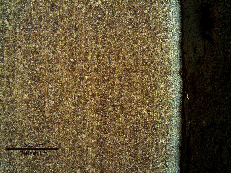 Micrography of a longitudinal section of the pipe, at the internal pipe surface,  where the coating was detached.  The strain hardening effect of the blasting is evident. The microstructure is tempered martensite and the  surface is slightly decarburized.