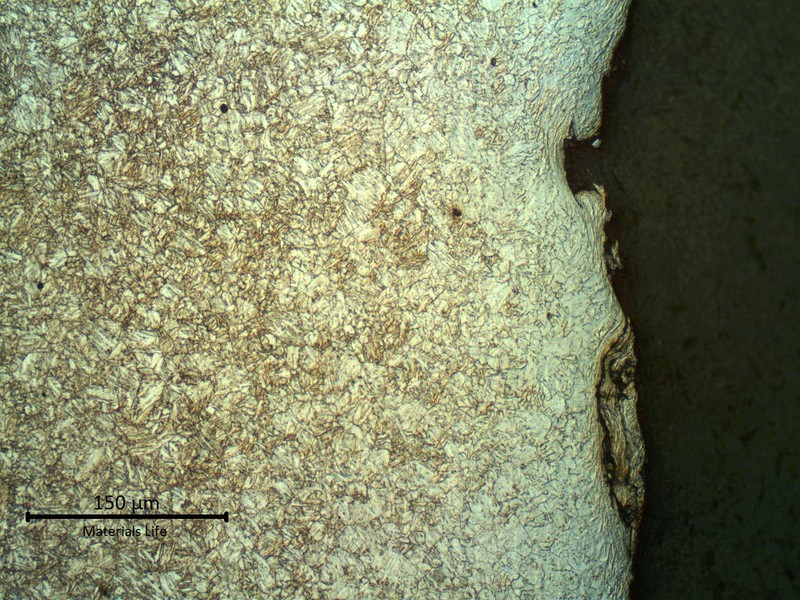 Micrography of a longitudinal section of the pipe, at the internal pipe surface, where the coating was detached. The strain hardening effect of the blasting is evident. The microstructure is tempered martensite and the surface is slightly decarburized.