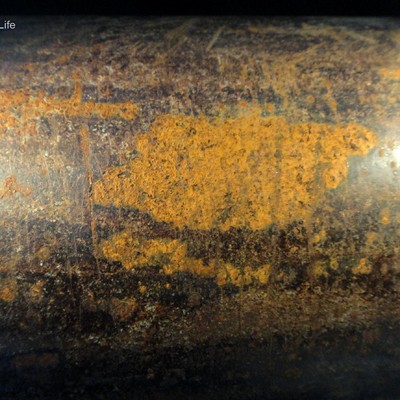 Pipe body surface, adjacent to the fracture, showing regions of corrosion and visual cracks transverse to the pipe axis.