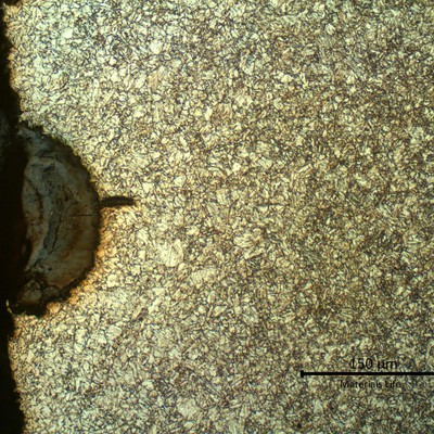 Micrography of a longitudinal section of the pipe, at the external pipe surface,  where there is a crack propagating from the corroded spot.  The microstructure is tempered martensite and at the surface the pipe is slightly decarburized.