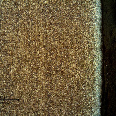 Micrography of a longitudinal section of the pipe, at the internal pipe surface,  where the coating was detached.  The strain hardening effect of the blasting is evident. The microstructure is tempered martensite and the  surface is slightly decarburized.