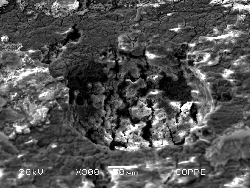 Microscopic detail, by scanning electron microscope,  of a region where there is a localized dissolution at the internal surface of the tube. The deposits are adhered at the surface and under the deposits, the analysis indicated increased sulfur levels, suggesting SRB (sulfate reduced bacteria) effects.