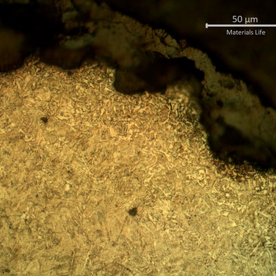 Micrographic detail of spring surface, showing the pits full of corrosion deposits and a small decarburized layer (probably from the manufacturing processes).