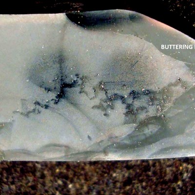 This macrography shows a longitudinal section of the tubular cast fitting.  The external side is to the top and the internal side to the bottom.  The buttering layer is evident in the groove that would be welded to the centrifugall cast tube (right side) and part of the ID and OD.  During the buttering welding of the casting the cracks were not detected because they were formed  in the center of the thickness and some have propagated to the internal diameter, but not to the external diameter. They opened only when the buttered casting was welded to the tube.