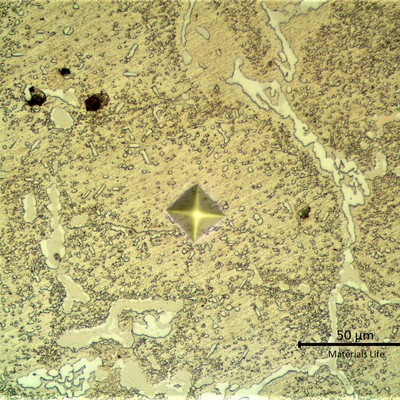 Aged microstructure of the HP stainless steel, modified with 1%Nb, cast fitting, tubular, operating for 6 years in a furnace which design temperature is 1100°C. The material presented a network of primary carbides, white and grey, and an austenitic matrix with coalescing secondary precipitation. Some voids. The Vickers identation indicates a hardness value about 260HV 100g in the aged austenitic matrix.