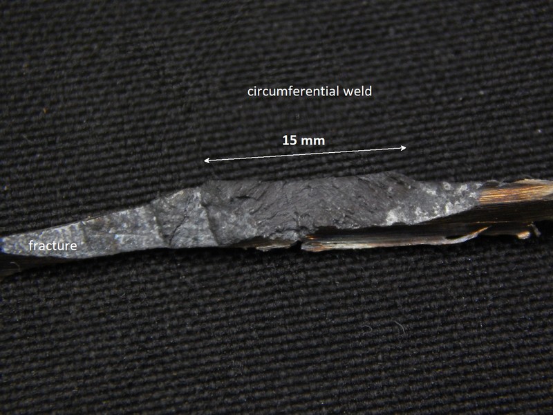 The small wedge sample is 4 mm deep in the thickness and the circumferential weld are is about 15 mm width where it appears in the internal side of the carcass. The image shows the crack surface (fracture) where the weld aspect is evident.