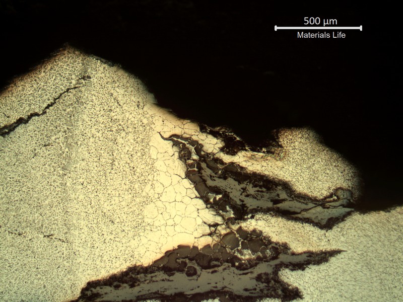 Sample surface. Microstructure of the heat affected zone (weld metal to the left side and base metal to the right side), exposed to high temperature exhausting gases. Large austenitic grain size and cracks fully opened and filled with oxides.