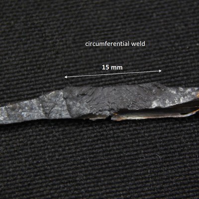 The small wedge sample is 4 mm deep in the thickness and the circumferential weld are is about 15 mm width where it appears in the internal side of the carcass.  The image shows the crack surface (fracture) where the weld aspect is evident.