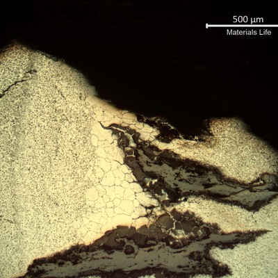 Sample surface. Microstructure of the heat affected zone (weld metal to the left side and base metal to the right side), exposed to high temperature exhausting gases.  Large austenitic grain size and cracks fully opened and filled with oxides.