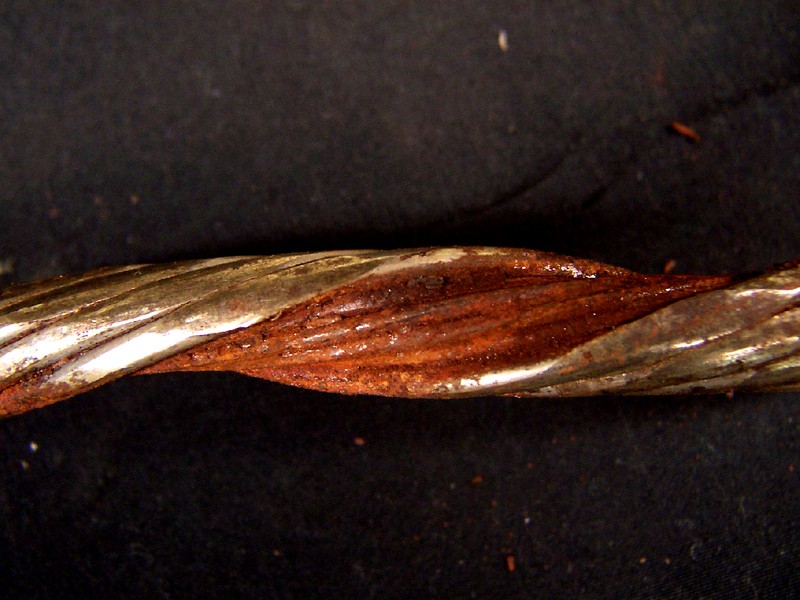 One disassembled strand without the core of the strand, showing an internal rusted surface, and externally flattened areas (left side of the figure).