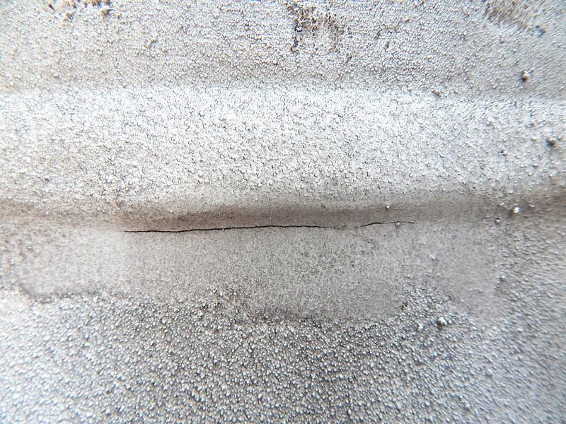 The dye check image shows the detected crack, 50 mm long, at the margin of the weld in the forging side.