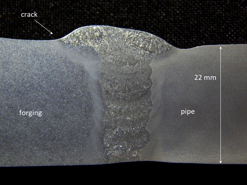 Macrography of the welded joint between the forging and the pipe, showing it was welded in a narrow gap, indicating by the arrow the location of the crack at the margin of the weld, in the forging side.