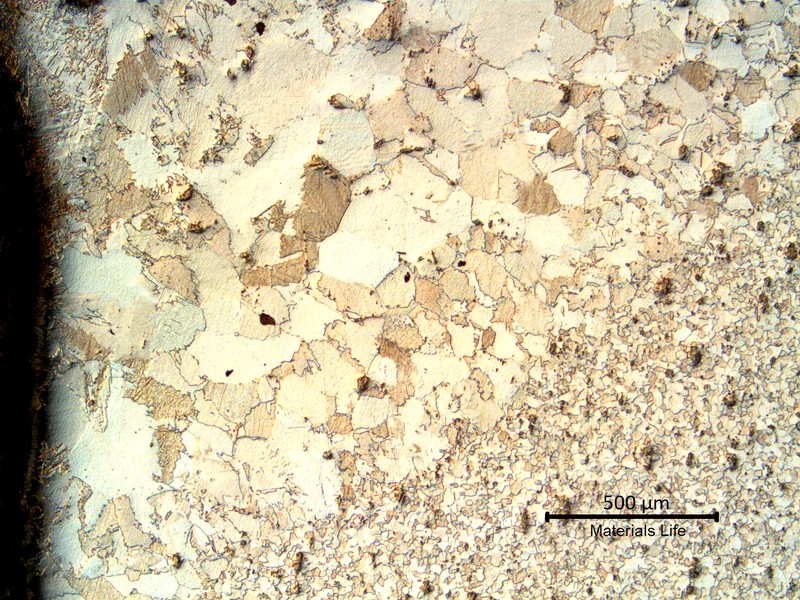 Low magnification micrography transverse to the fillet weld in the pipe. The pipe base metal is to the bottom of the figure and the weld metal is to the top. The heat affected zone in the middle, shows a coarse grain size structure.