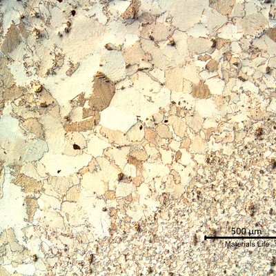 Low magnification micrography transverse to the fillet weld in the pipe. The pipe base metal is to the bottom of the figure and the weld metal is to the top. The heat affected zone in the middle, shows a coarse grain size structure.