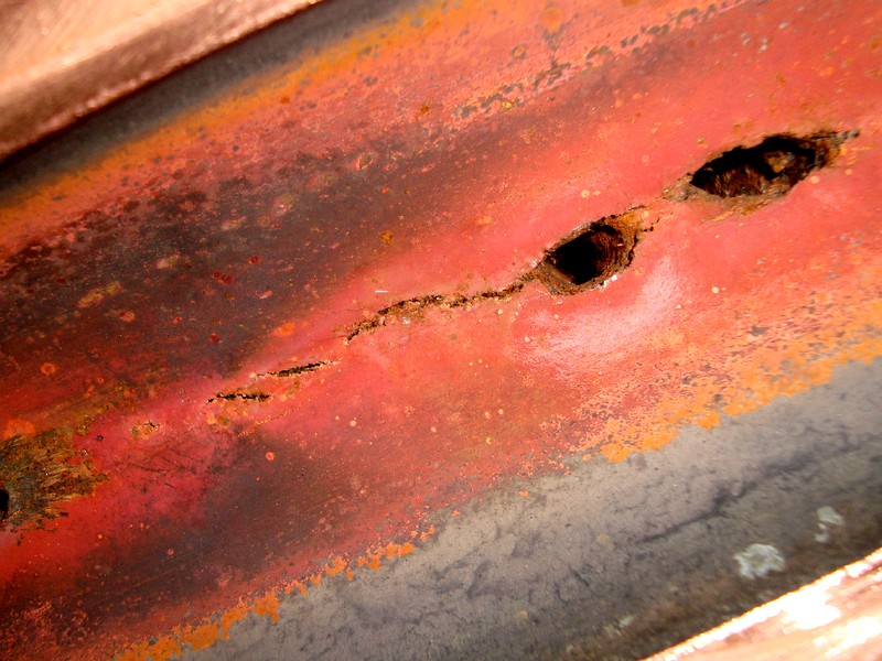 Detail of the perforation point, internal view. Aligned perforations in the overheated region and interconnected longitudinal cracks.