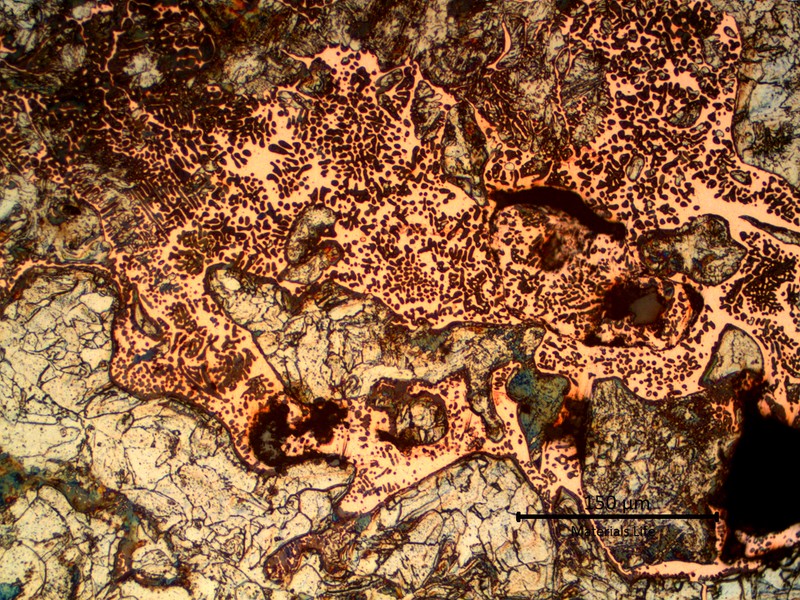Micrographic detail of the melted materials. Grey islands of steel and the dendritic structure of the orange copper and dark dots (probably due to oxygen contamination).