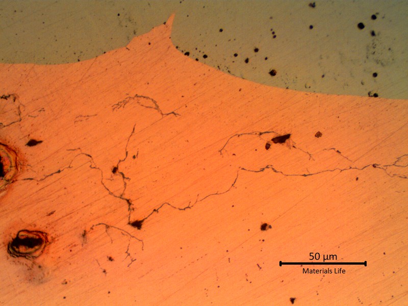 Micrographic aspect, as polished, of a transverse section of the tube (bottom side of the image, orange), at the interface between the tube and the melted steel over the external diameter (top side of the image, grey). In the copper tube there are several microcracks and regions of incipient melting (voids).
