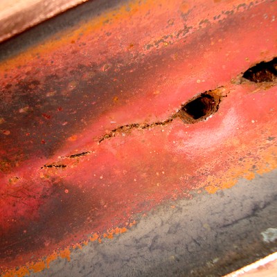 Detail of the perforation point, internal view. Aligned perforations in the overheated region and interconnected longitudinal cracks.