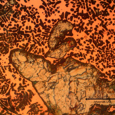 Micrographic detail of the melted materials. Grey islands of steel (with grains) and the dendritic structure of the orange copper and dark dots (probably due to oxygen contamination).