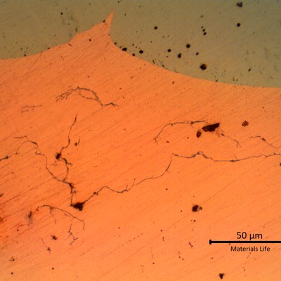 Micrographic aspect, as polished, of a transverse section of the tube (bottom side of the image, orange), at the interface between the tube and the melted steel over the external diameter (top side of the image, grey). In the copper tube there are several microcracks and regions of incipient melting (voids).