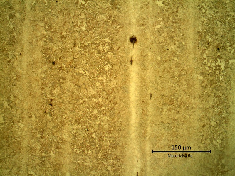 Micrography presenting segregation bands (less etched) in a tempered martensitic microstructure.