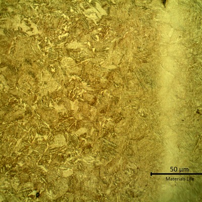 Micrography presenting a tempered martensitic microstructure, with light etch in segregated bands.