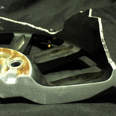 Macro view of a fractured wheel spoke section showing an irregular, shear-lip fracture edge consistent with ductile overload.