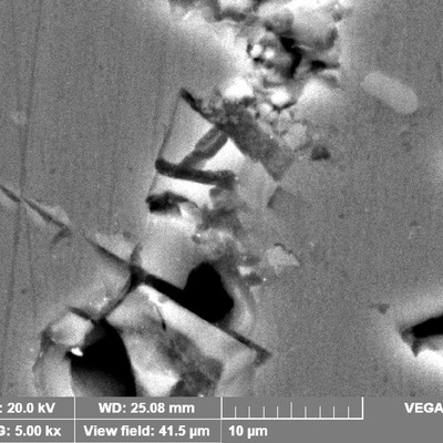 Detail of the brittle iron rich particles with several microcracks, that did not propagate during the impact that lead to the fracture.
